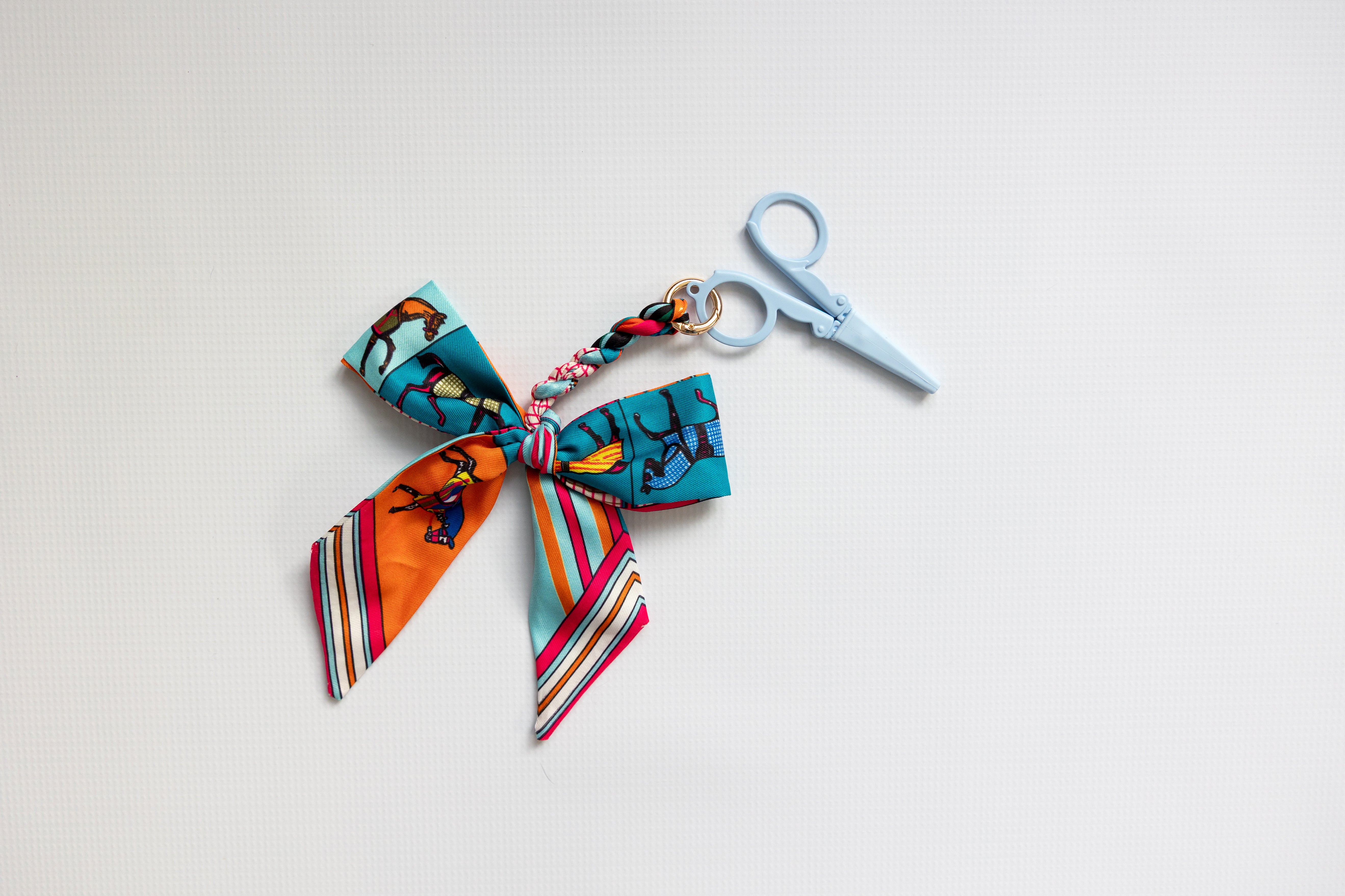 Colorful fabric bow with a keychain and scissors on a light background
