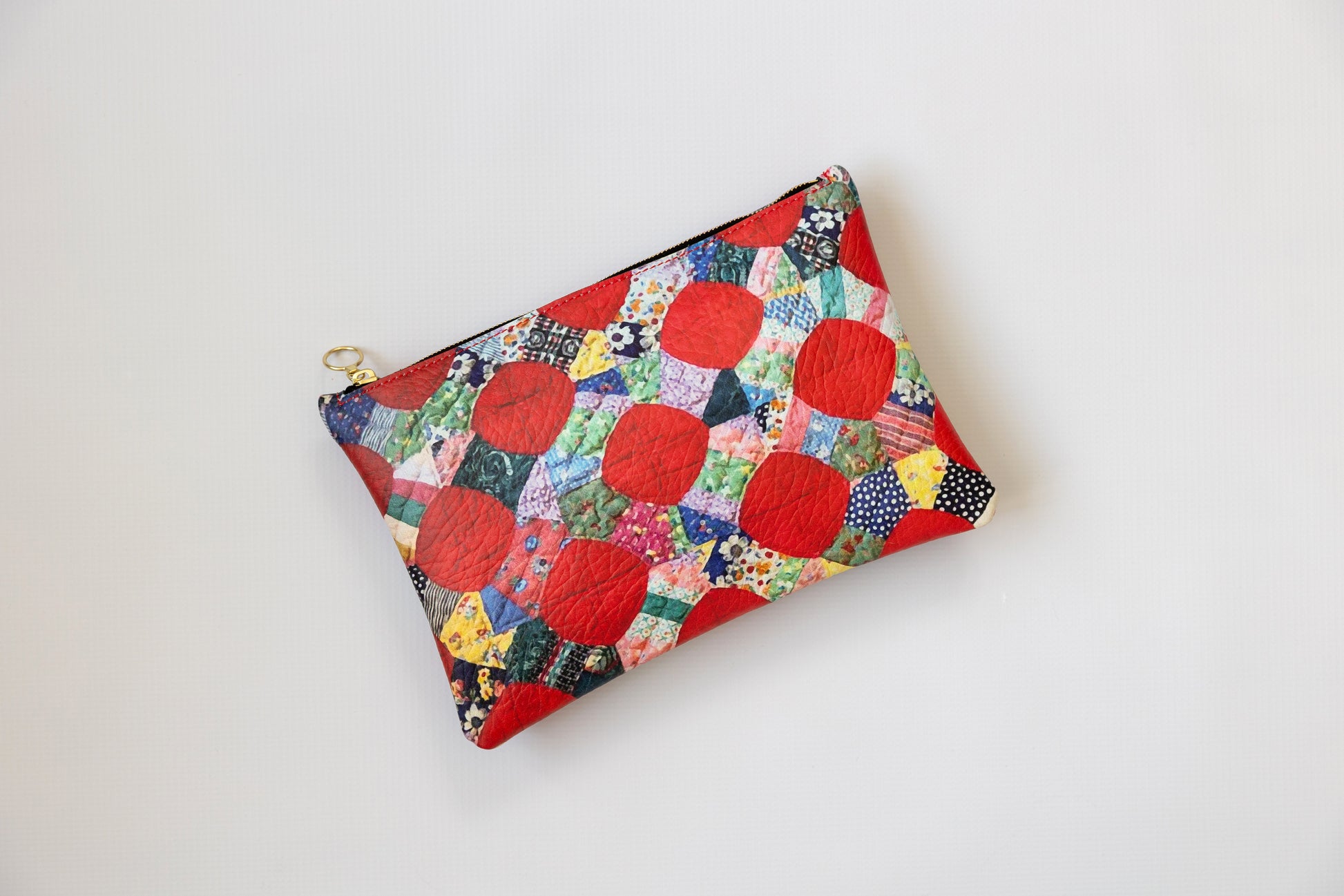 Colorful quilted pouch with red circles on a white background