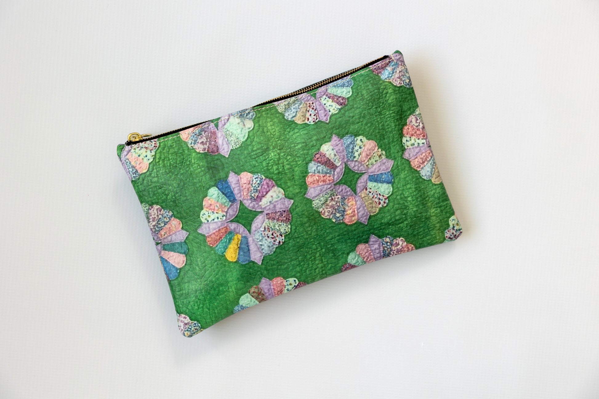 Green pouch with colorful geometric 
pattern on a white background