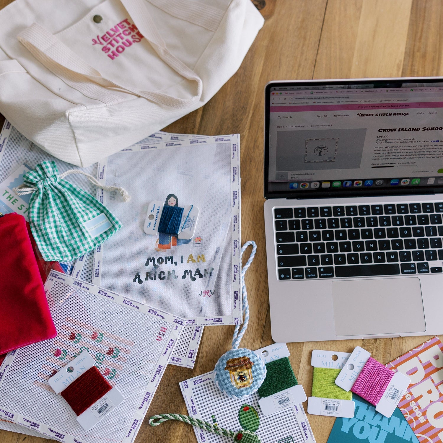 Laptop on a wooden table with various printed materials and stationery items.
