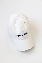 White cap with 'Apres Stitch' text in navy embroidery on a white background