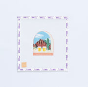 Needlepoint design of landscape with mountains and cacti and two beer mugs.