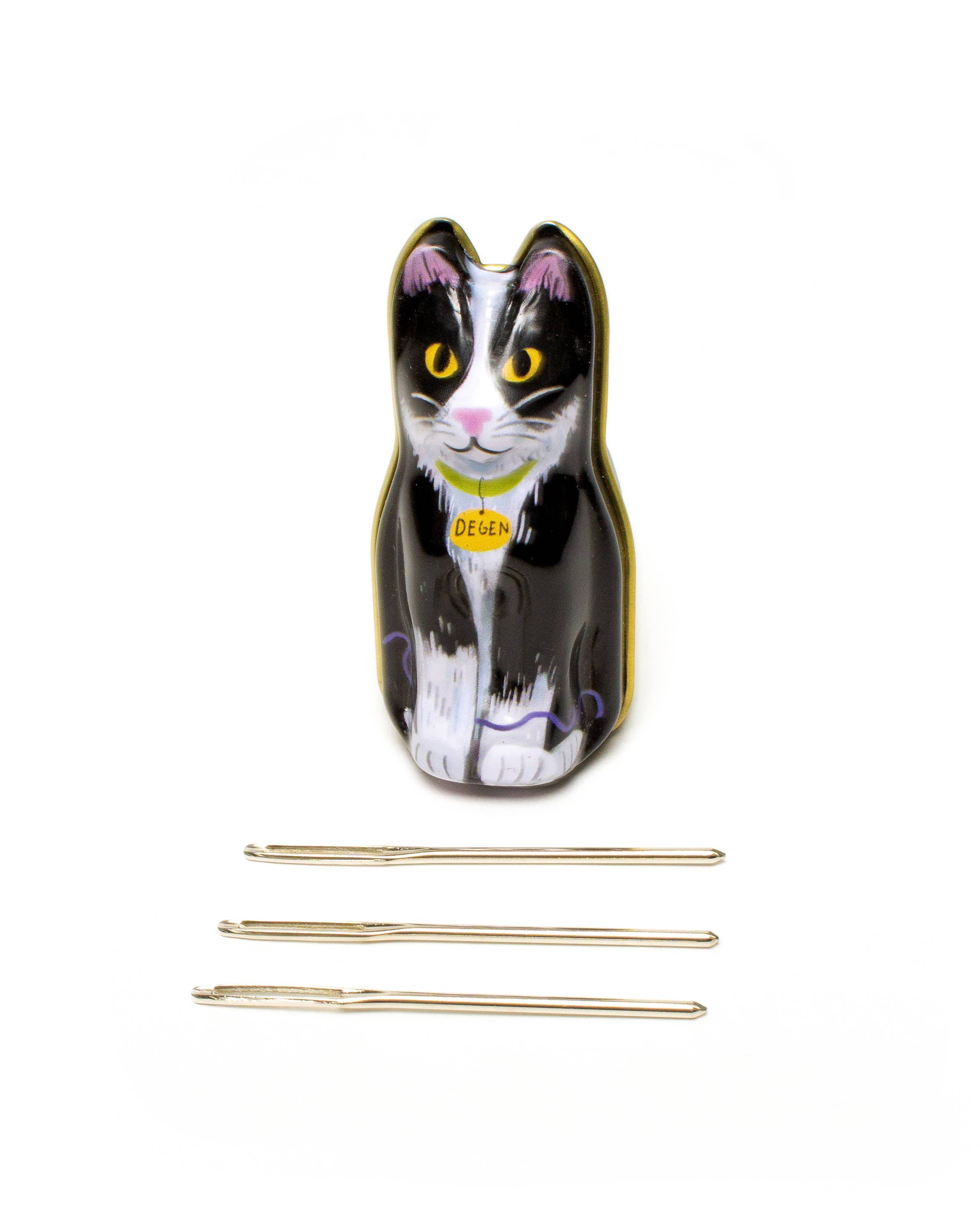 Cat-shaped knitting needle case with three gold knitting needles on a white background