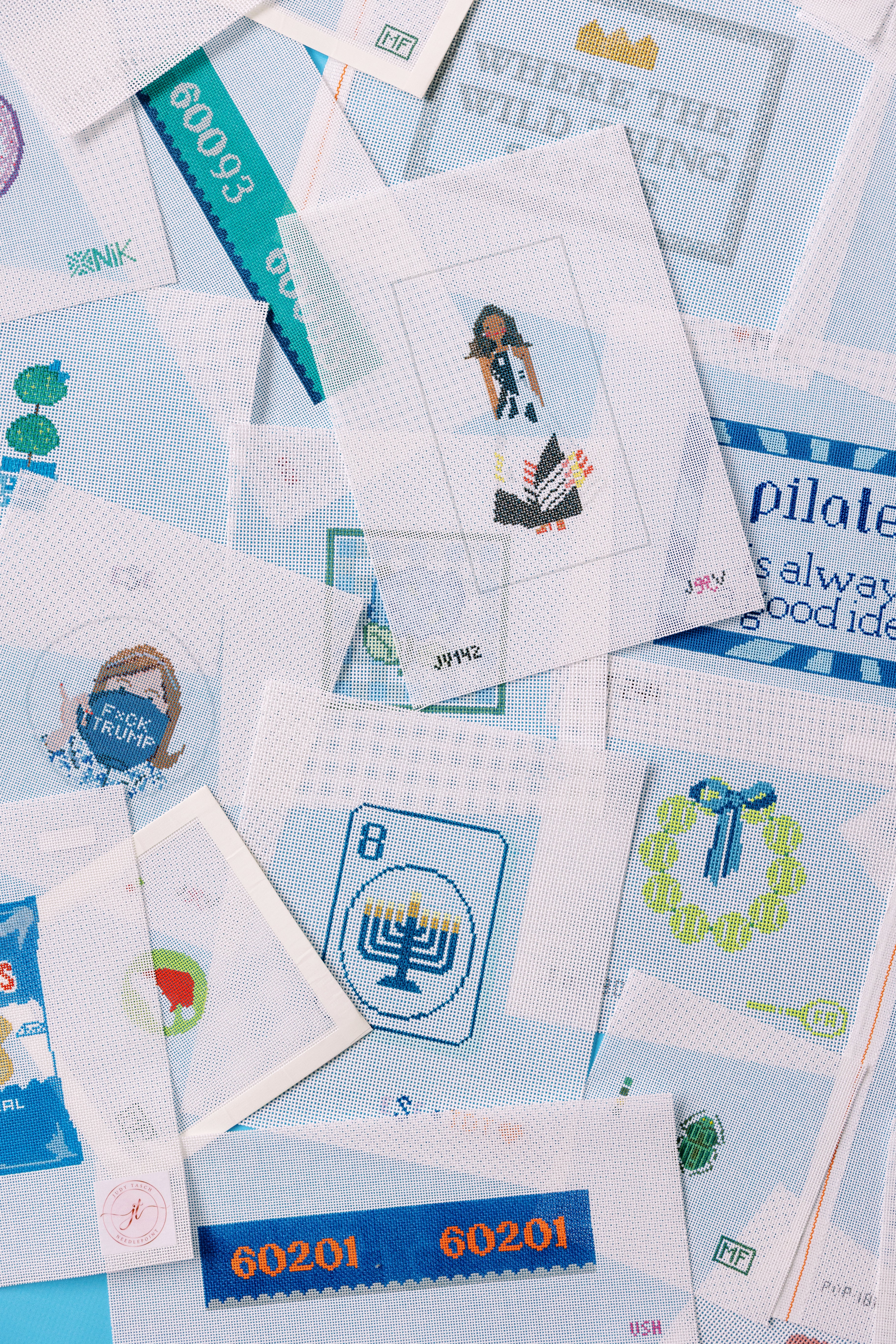 Collection of printed needlepoint canvas with various designs on a blue background