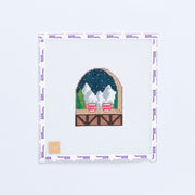 Needlepoint design of a snowy mountain scene with red mugs.