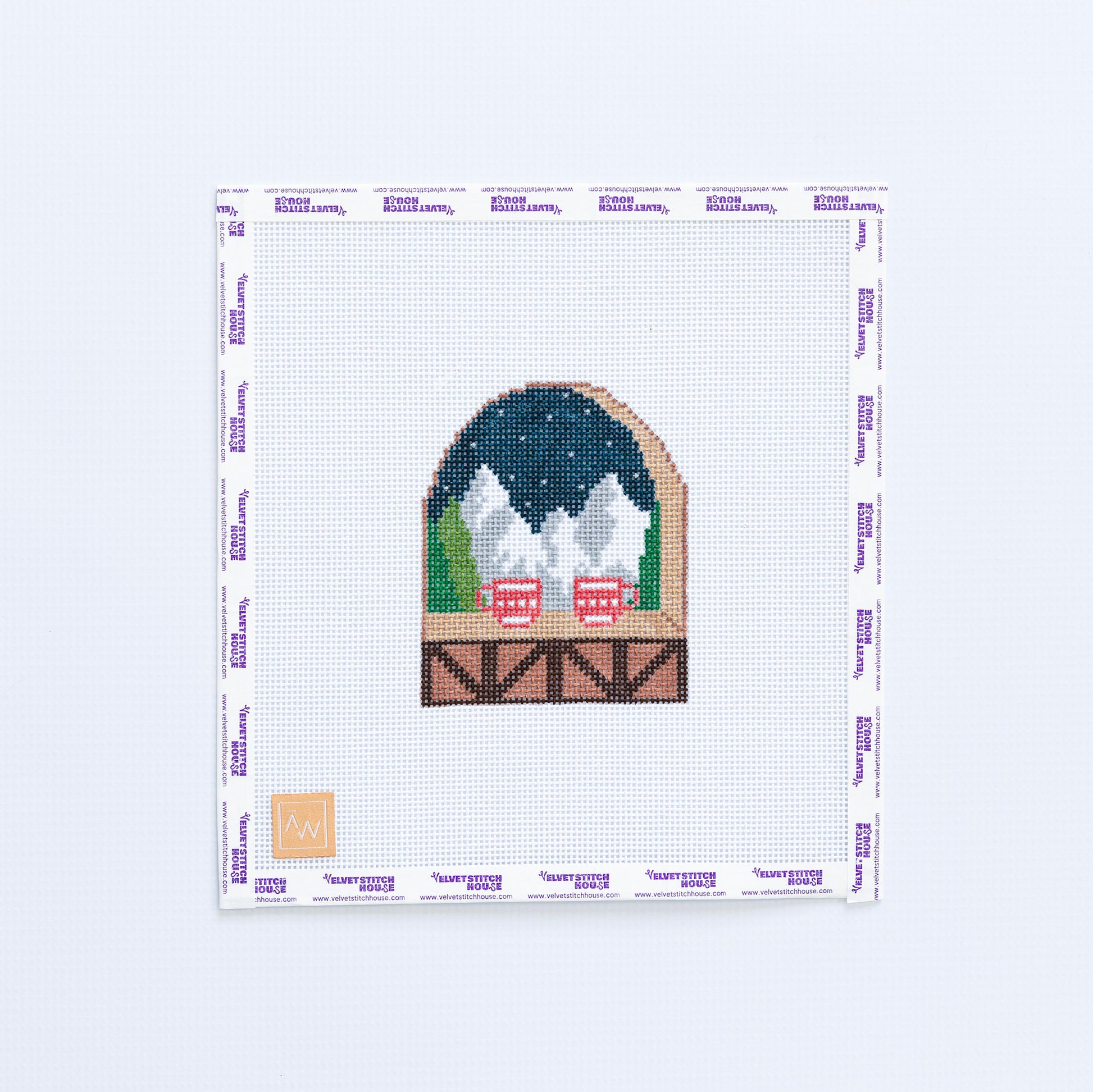 Needlepoint design of a snowy mountain scene with red mugs.