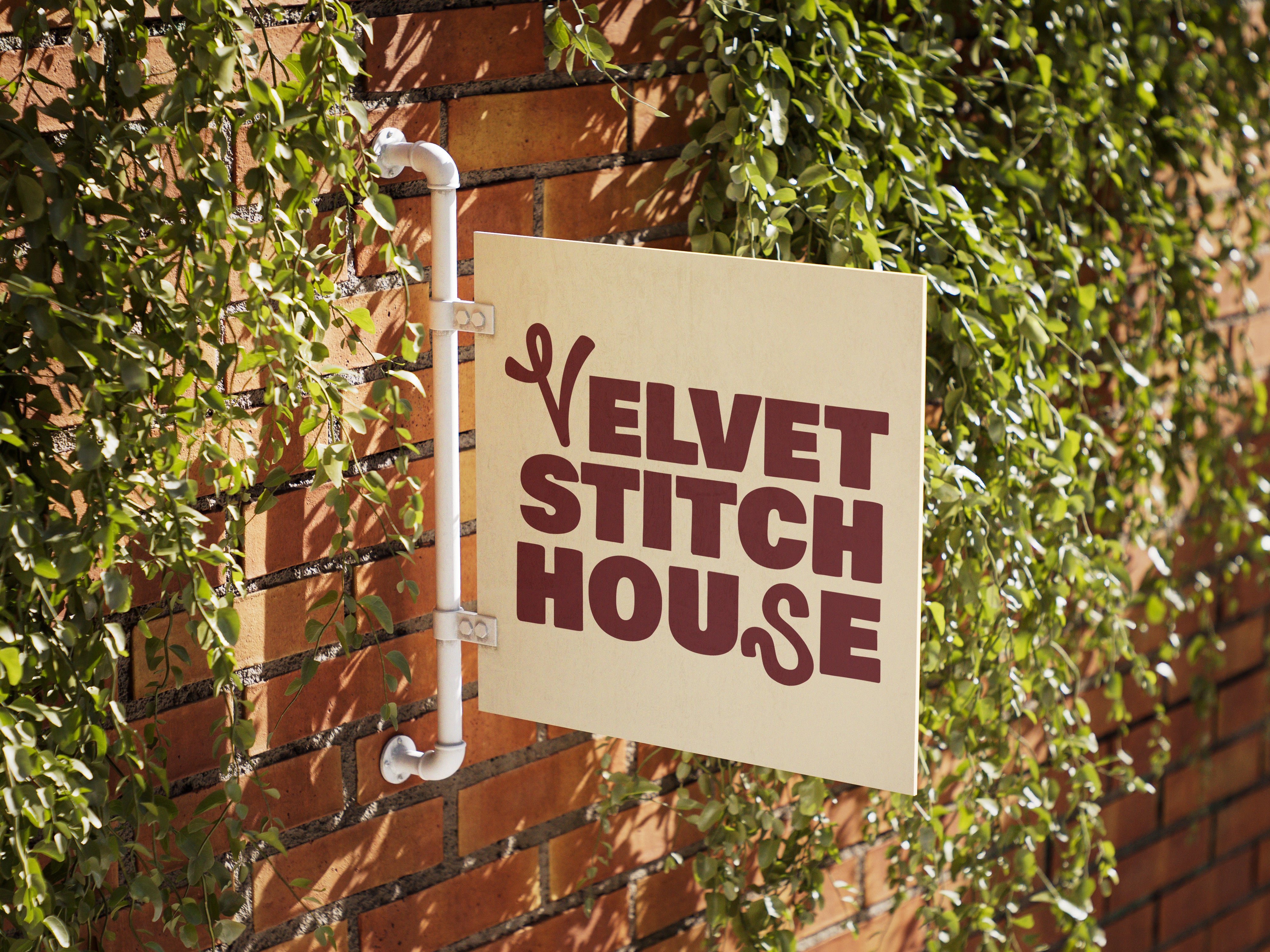 Velvet Stitch House logo on a white sign attached to a brick wall with ivy.