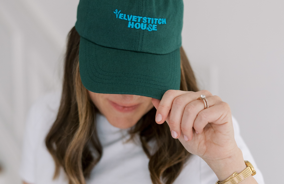 Person wearing a green cap with 'Velvet Stitch House' logo on a neutral background