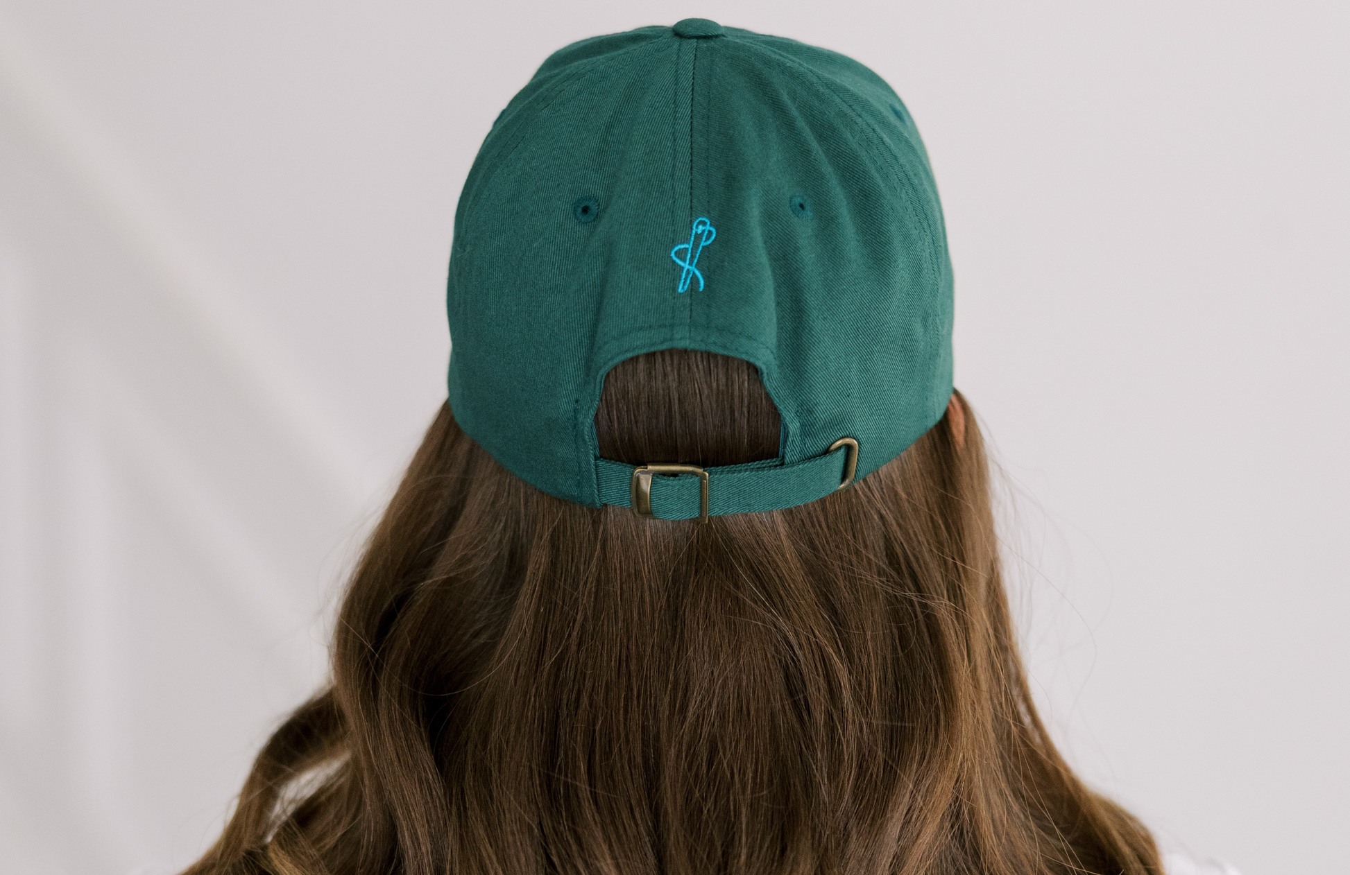 Back view of Green cap worn by a person with long hair on a plain background