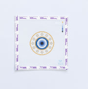 Needlepoint pattern of a blue and gold evil eye with a blue and gold circular design on a white fabric background