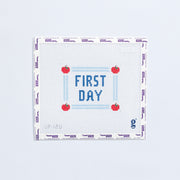 Needlepoint pattern with 'First Day' text and red apples on a white background