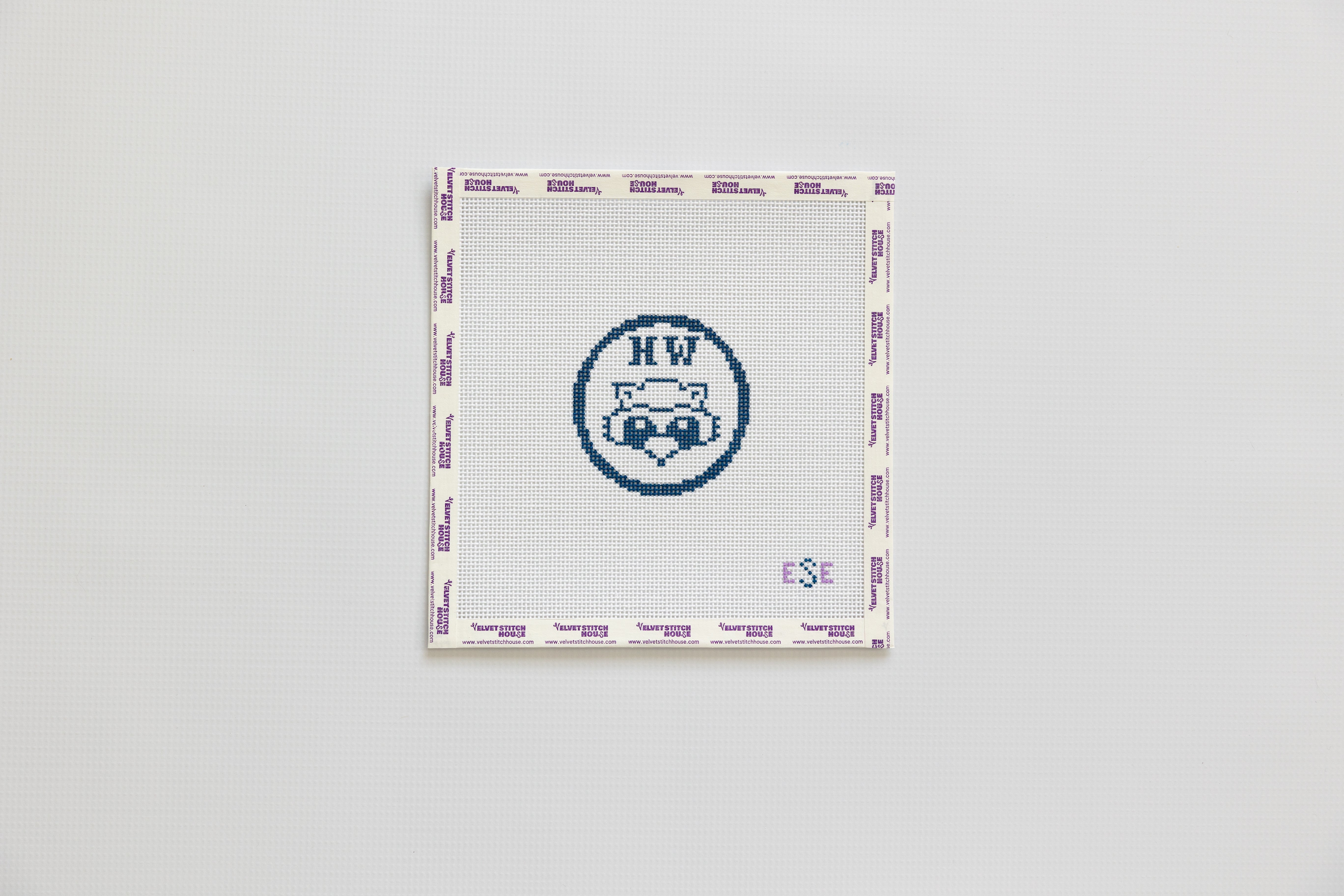 Needlepoint pattern with a logo and text on a gray background