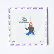 Needlepoint design of a person holding a 'We Shall Overcome' sign on a white background.