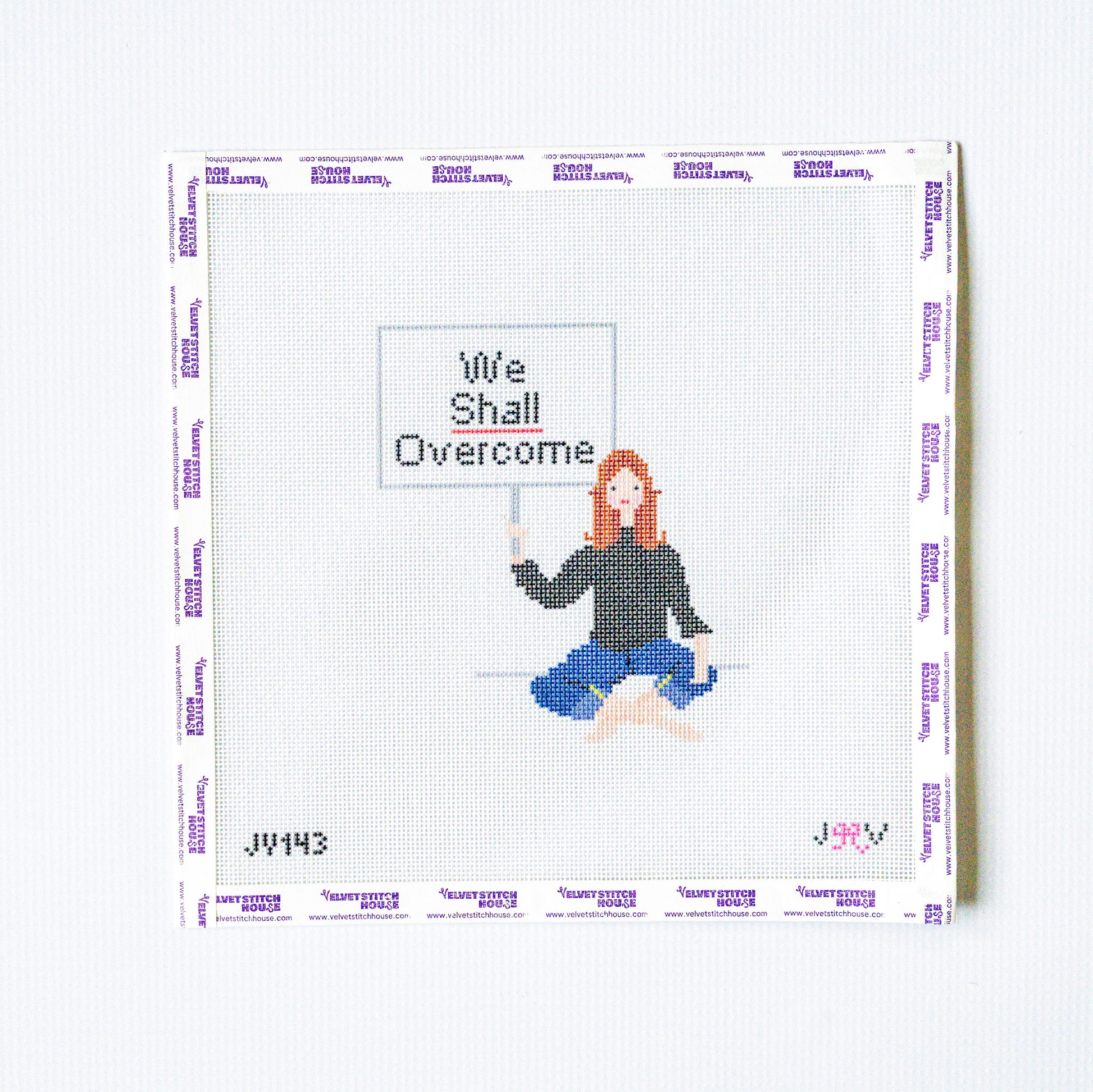 Needlepoint design of a person holding a 'We Shall Overcome' sign on a white background.