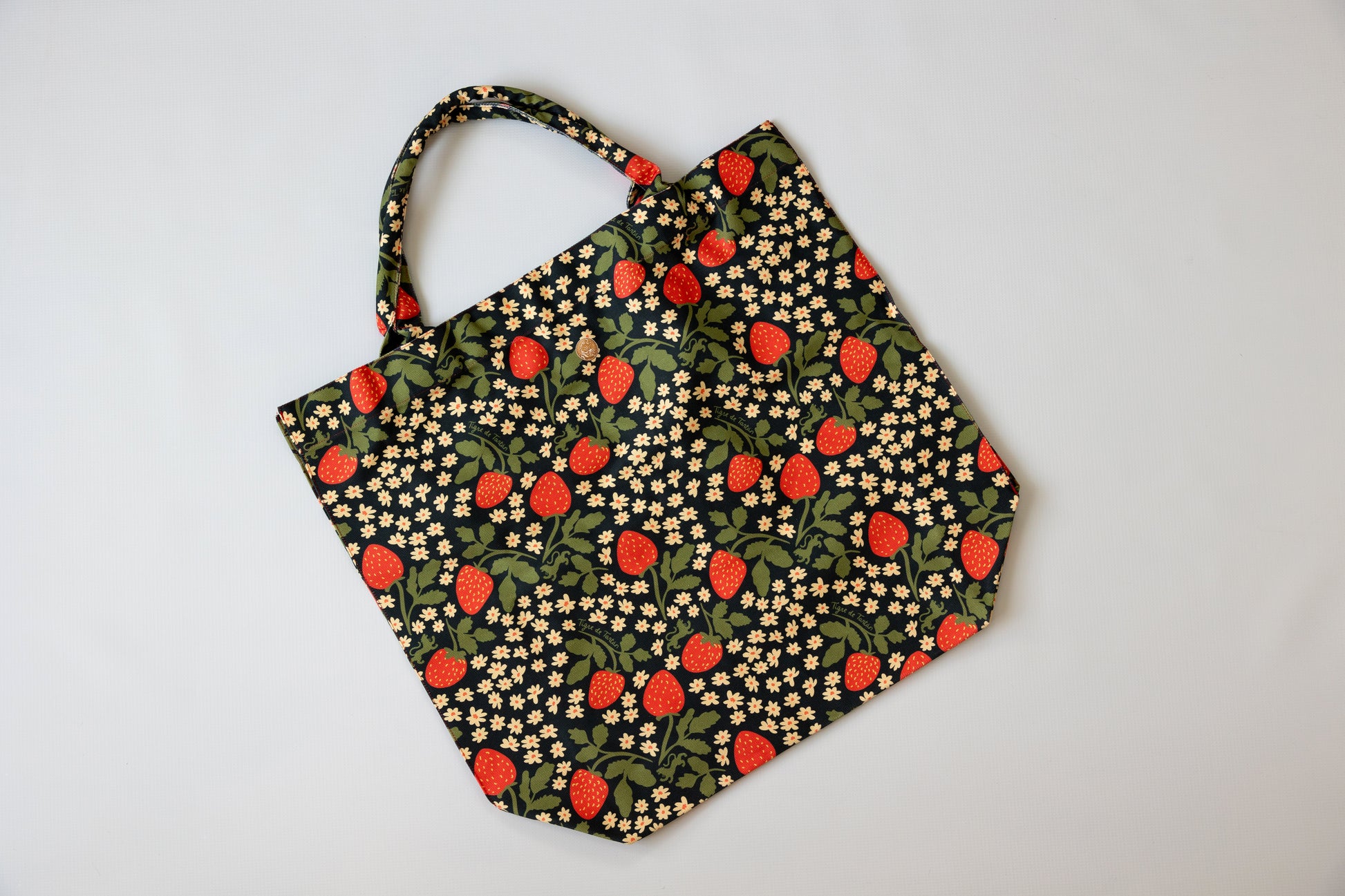 Fabric tote bag with strawberry pattern on a light gray background