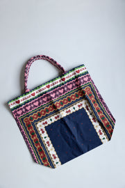 Colorful fabric bag with intricate patterns on a light gray background