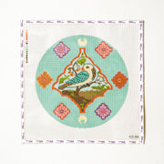 Needlepoint pattern of a bird and flowers on a light blue background with a white border.