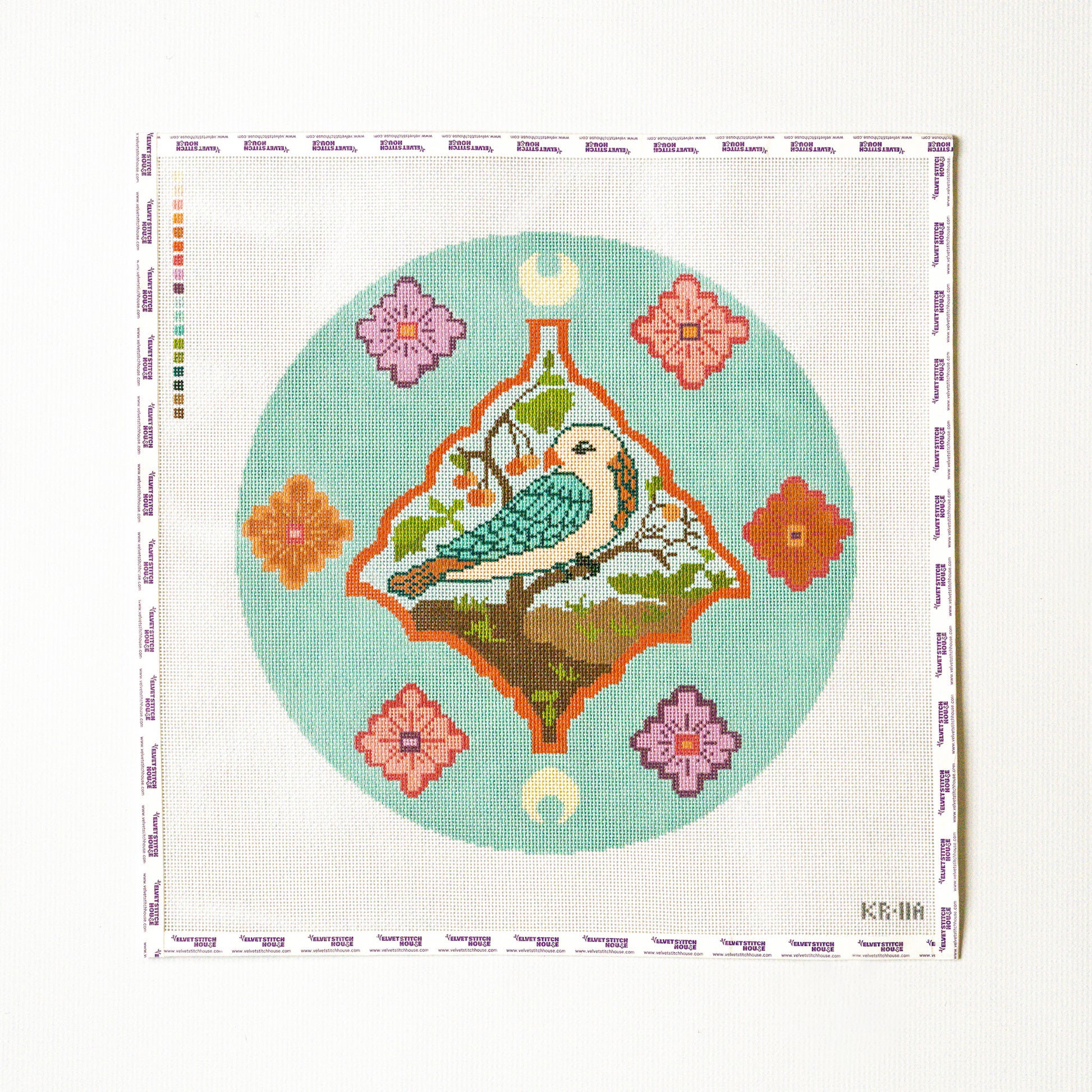 Needlepoint pattern of a bird and flowers on a light blue background with a white border.