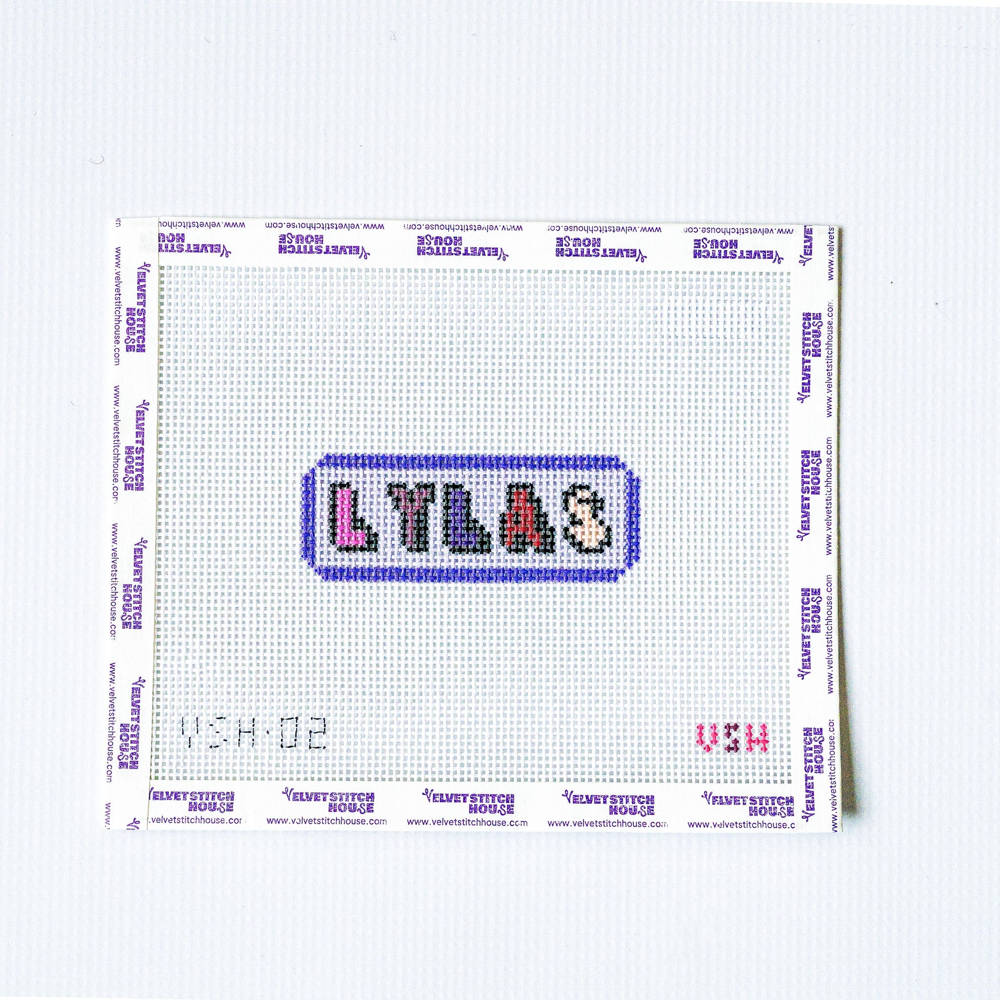 Needlepoint pattern with 'LYLAS' text on a white fabric background love you like a sister
