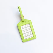 Green luggage tag with a white label on a light gray background