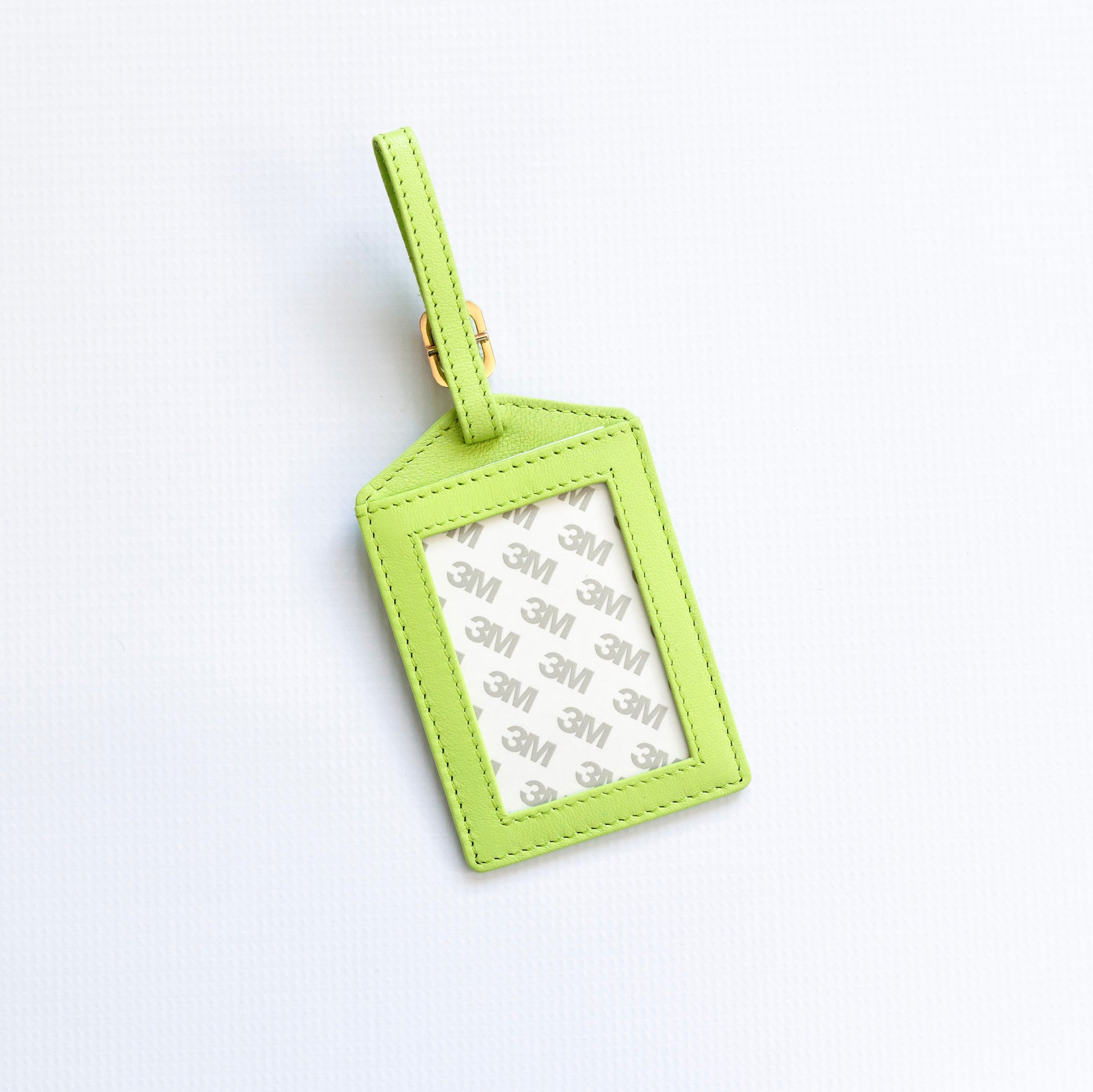 Green luggage tag with a white label on a light gray background