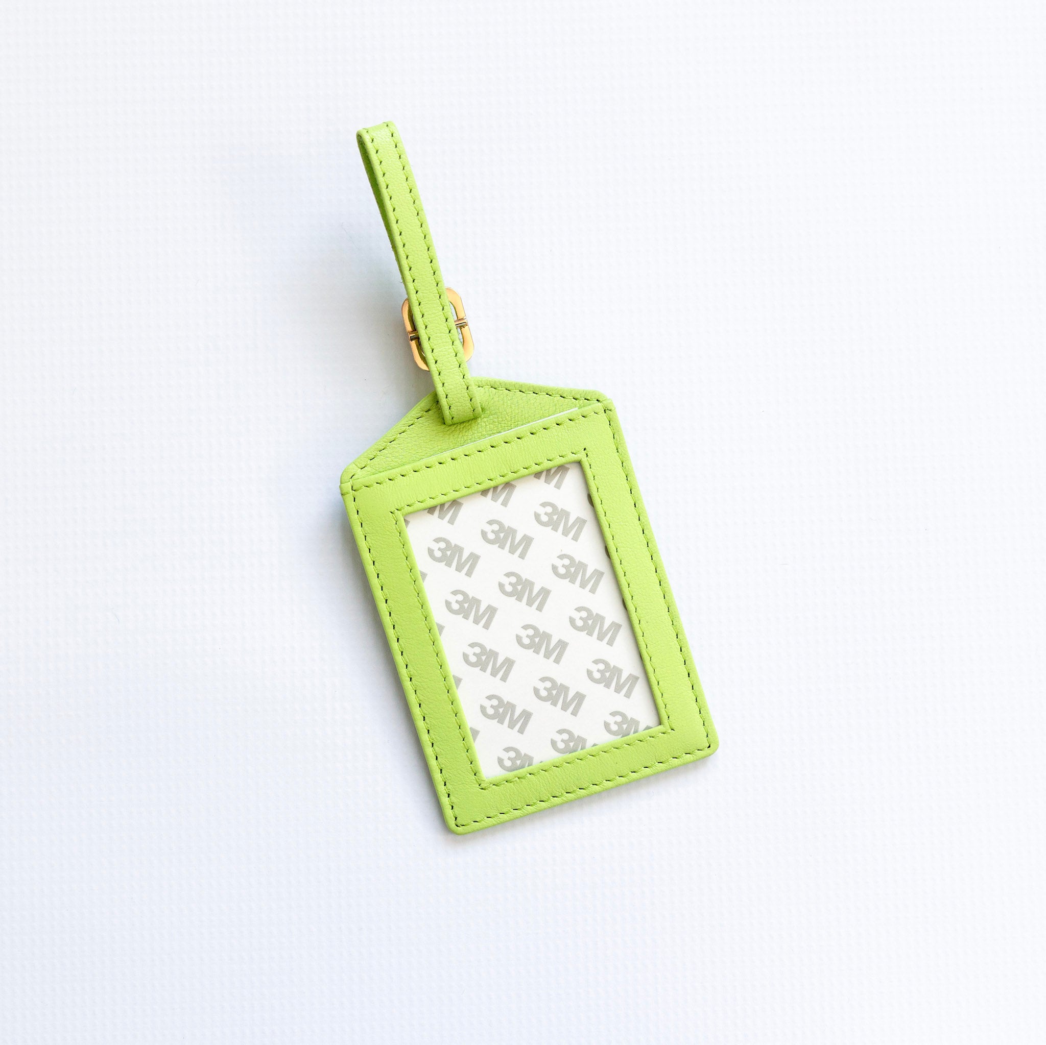 Green luggage tag with a white label on a light gray background