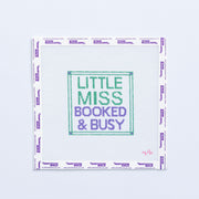 Needlepoint pattern with 'Little Miss Booked & Busy' green and purple text on a white background
