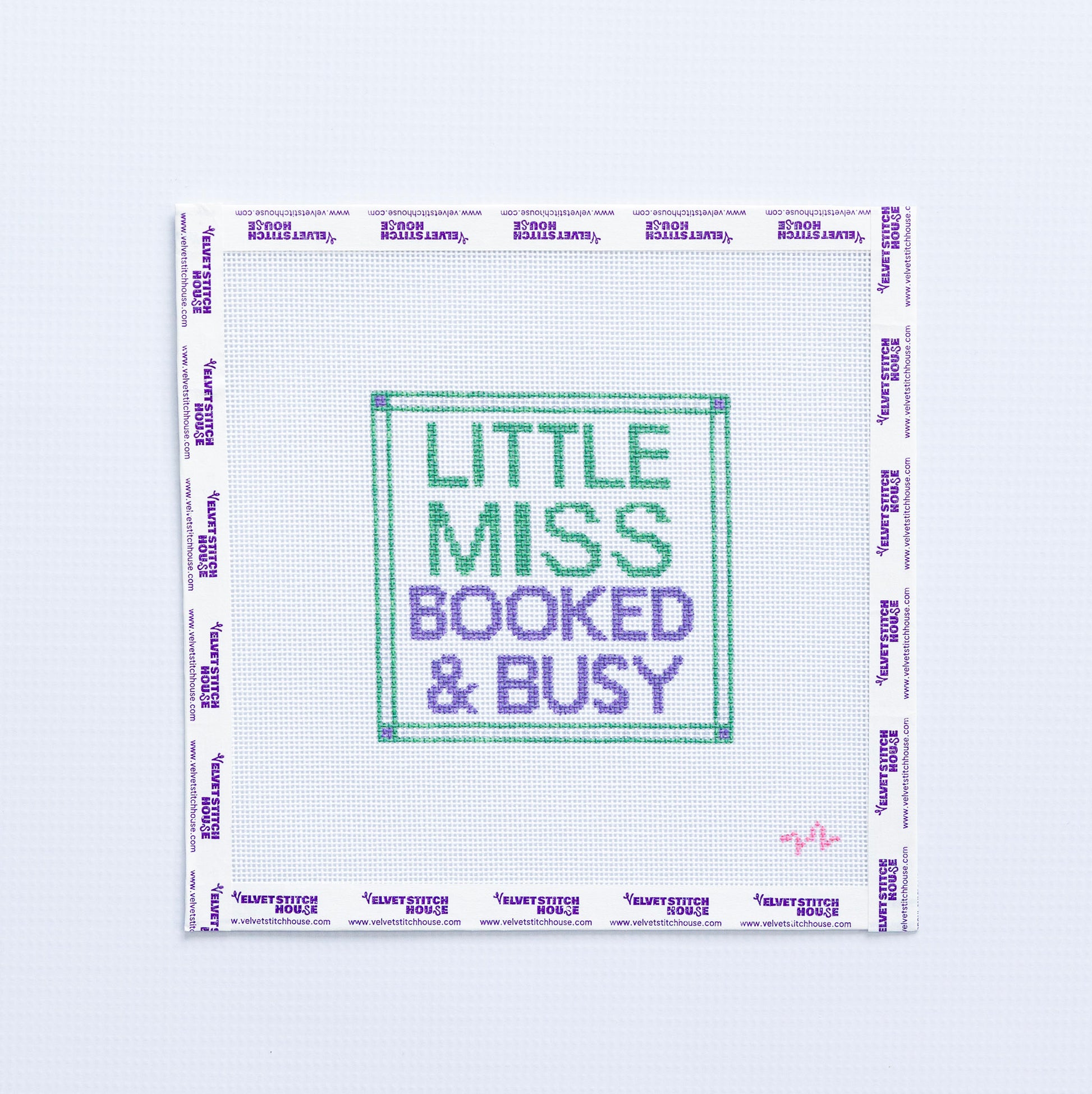 Needlepoint pattern with 'Little Miss Booked & Busy' green and purple text on a white background