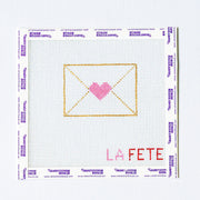 Needlepoint design of an envelope with a heart and 'LA FETE' text on a grid background.