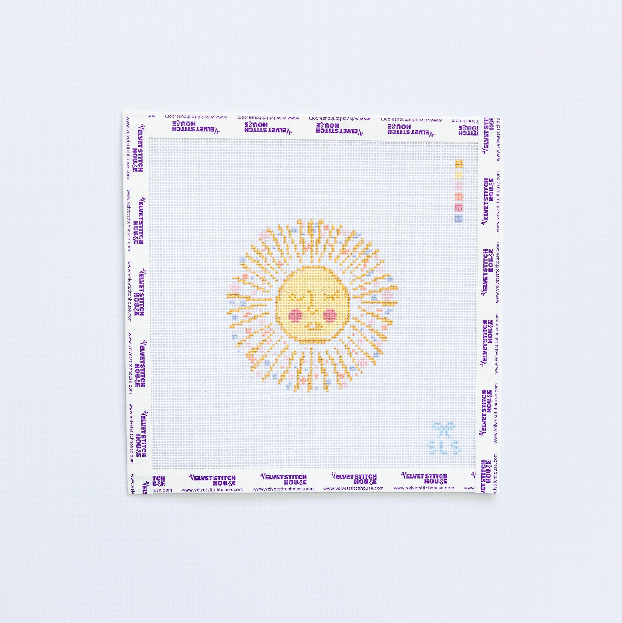 Needlepoint pattern of a yellow and gold sun with a face on a white background