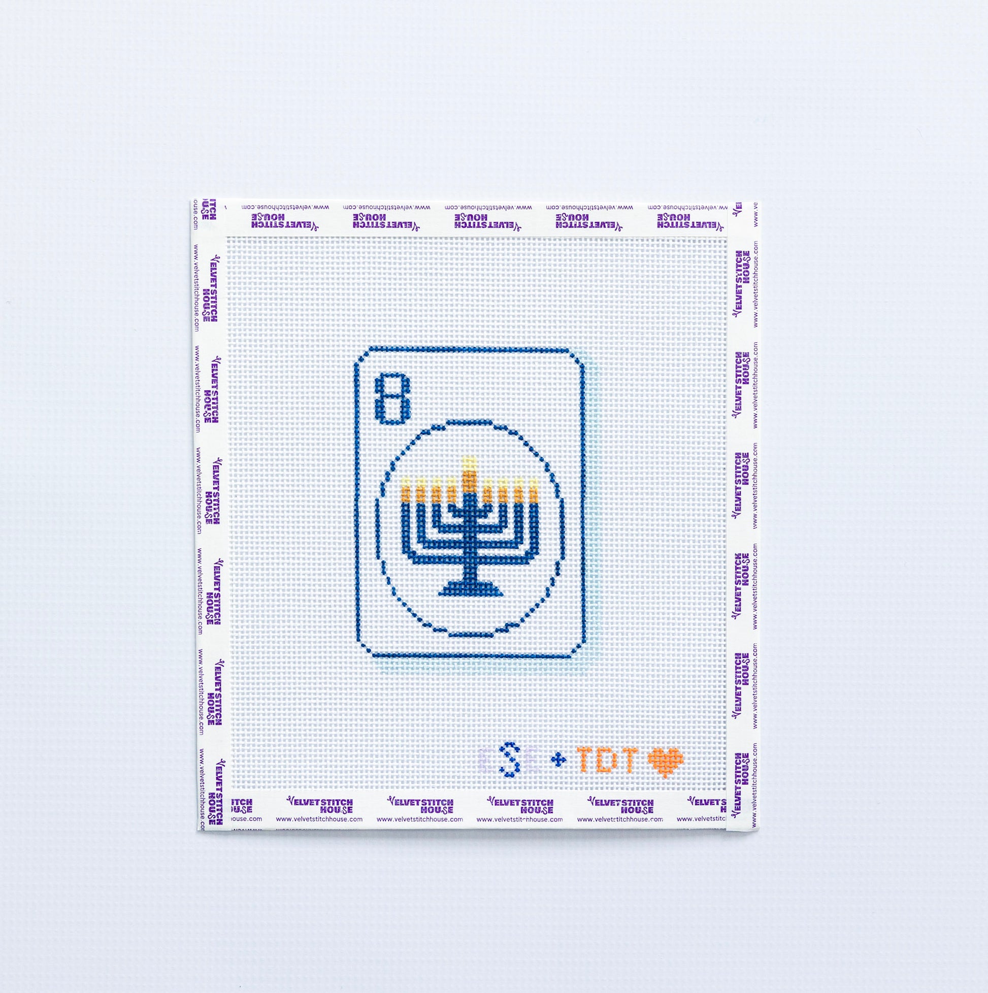 Needlepoint pattern with a menorah design in blue on a mahjong tile on a white background