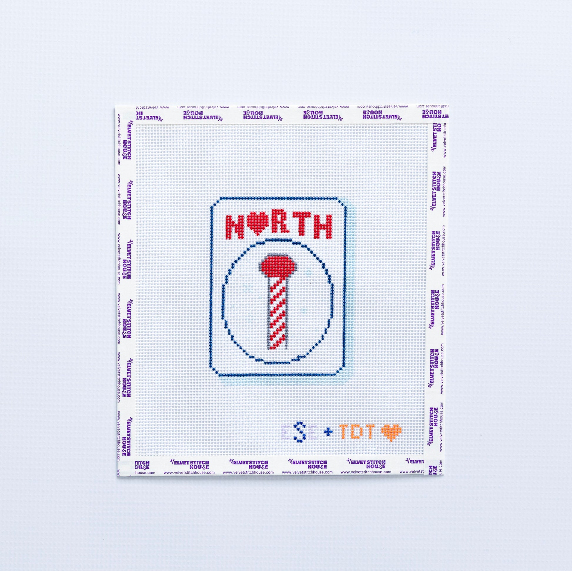 Needlepoint design with 'NORTH' in red and a candy cane pole on a mahjong tile on a white background