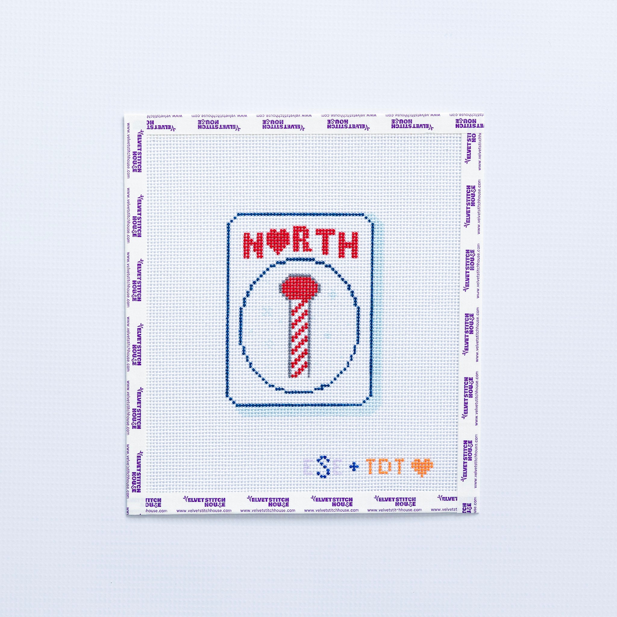 Needlepoint design with 'NORTH' in red and a candy cane pole on a mahjong tile on a white background