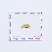 Mini needlepoint pattern with a smiling croissant design on a white background