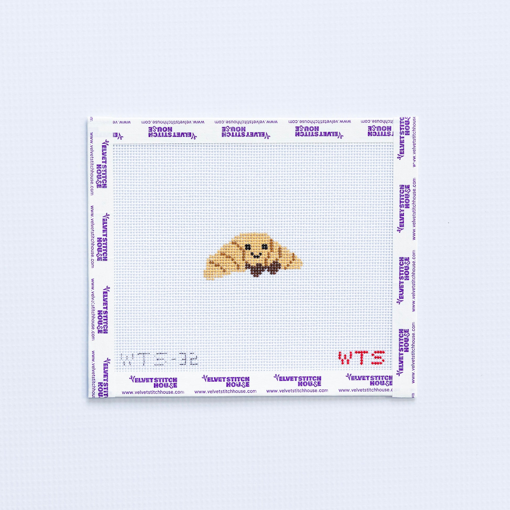 Mini needlepoint pattern with a smiling croissant design on a white background