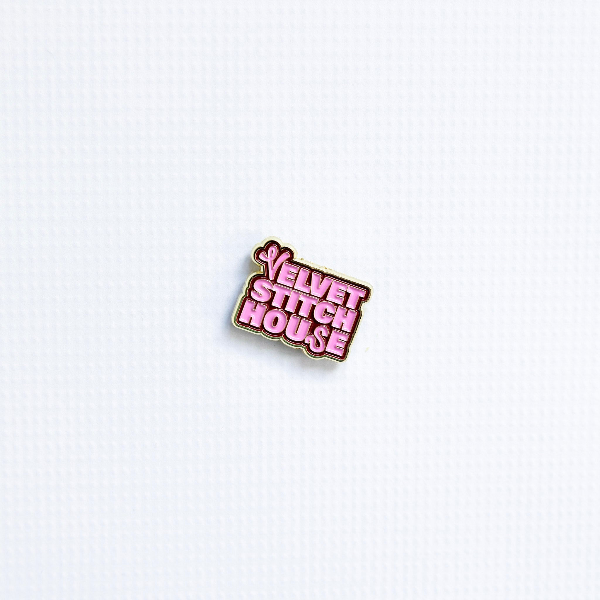 Enamel magnetic pin with 'Velvet Stitch House' text on a white background