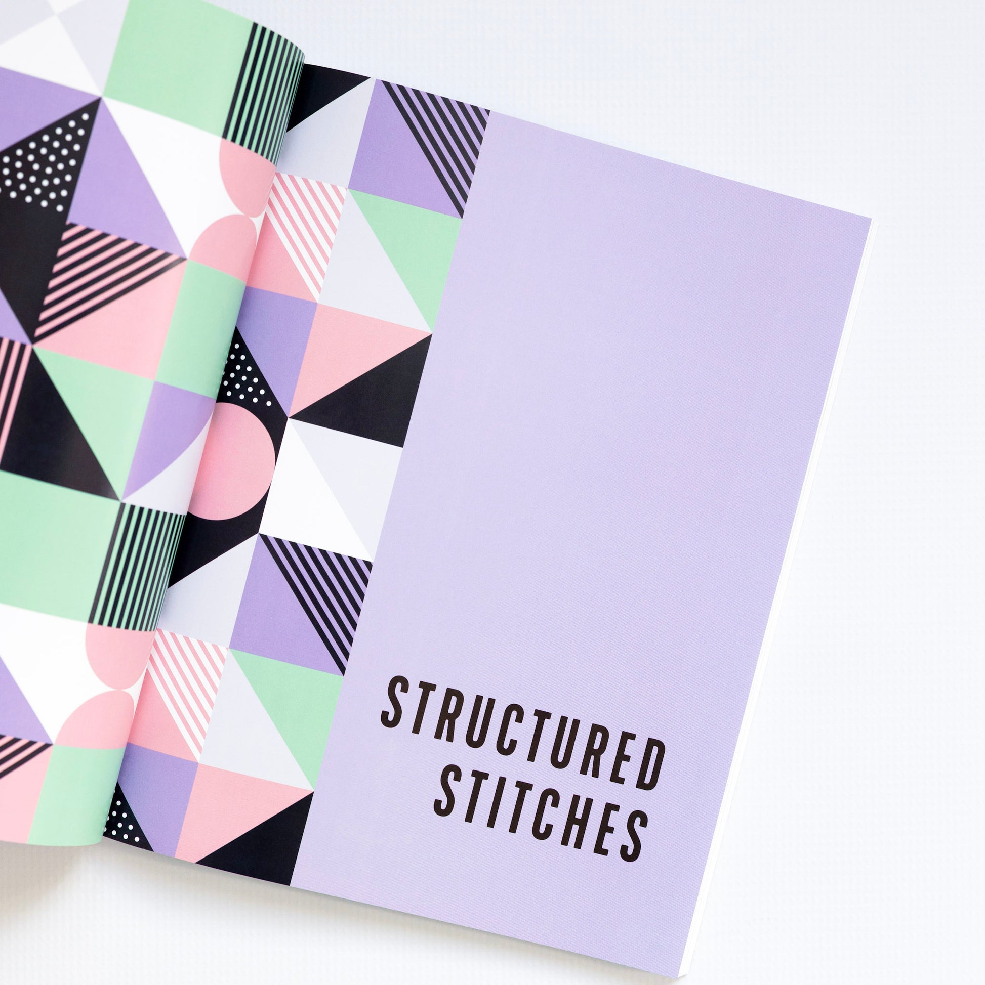 Notebook with geometric pattern and 'Structured Stitches' text on a white background