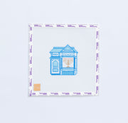 Needlepoint pattern with a blue house with a gold menorah in the window design on white background.