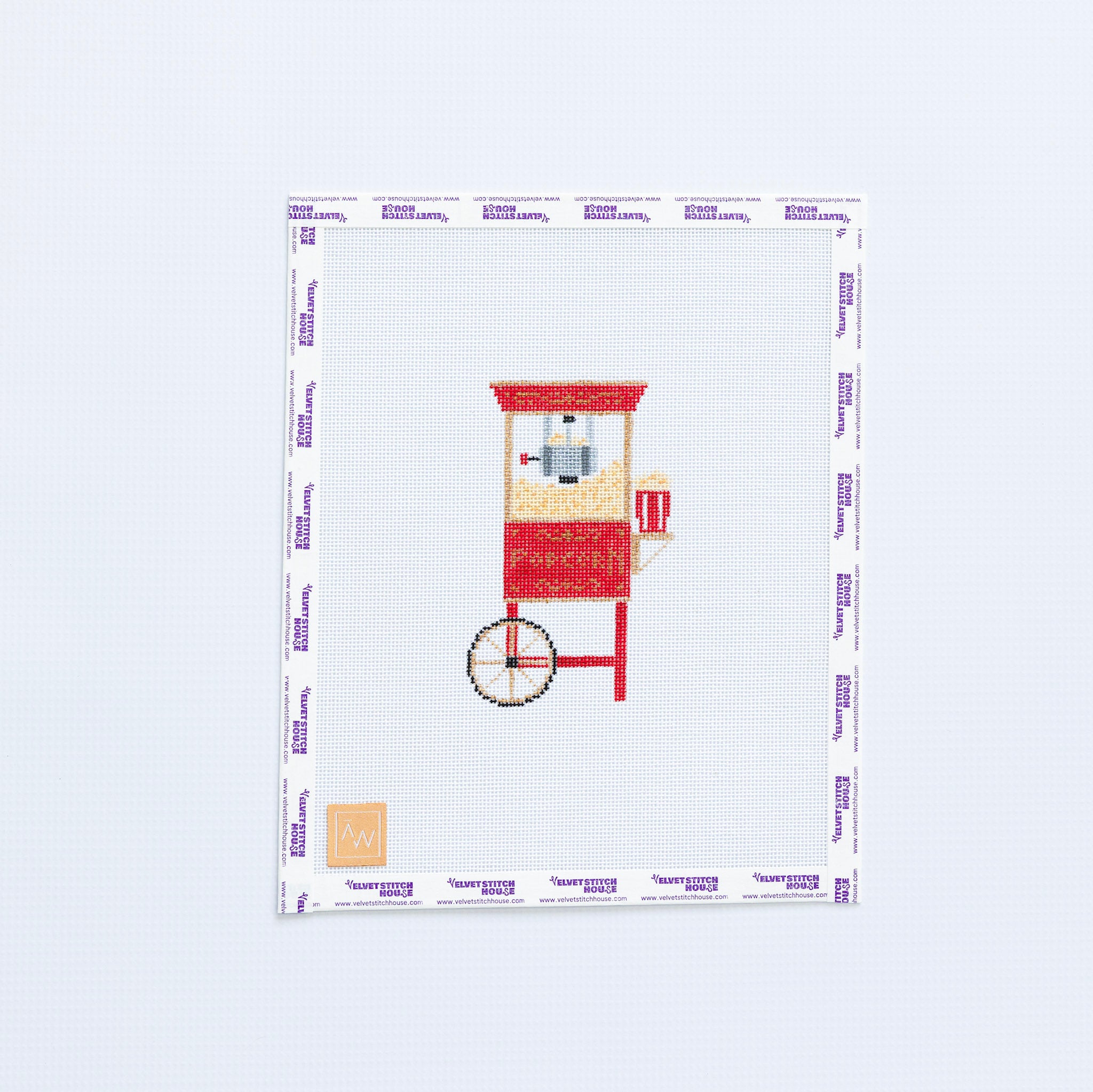 Needlepoint design of a red popcorn machine on a white fabric with a white background