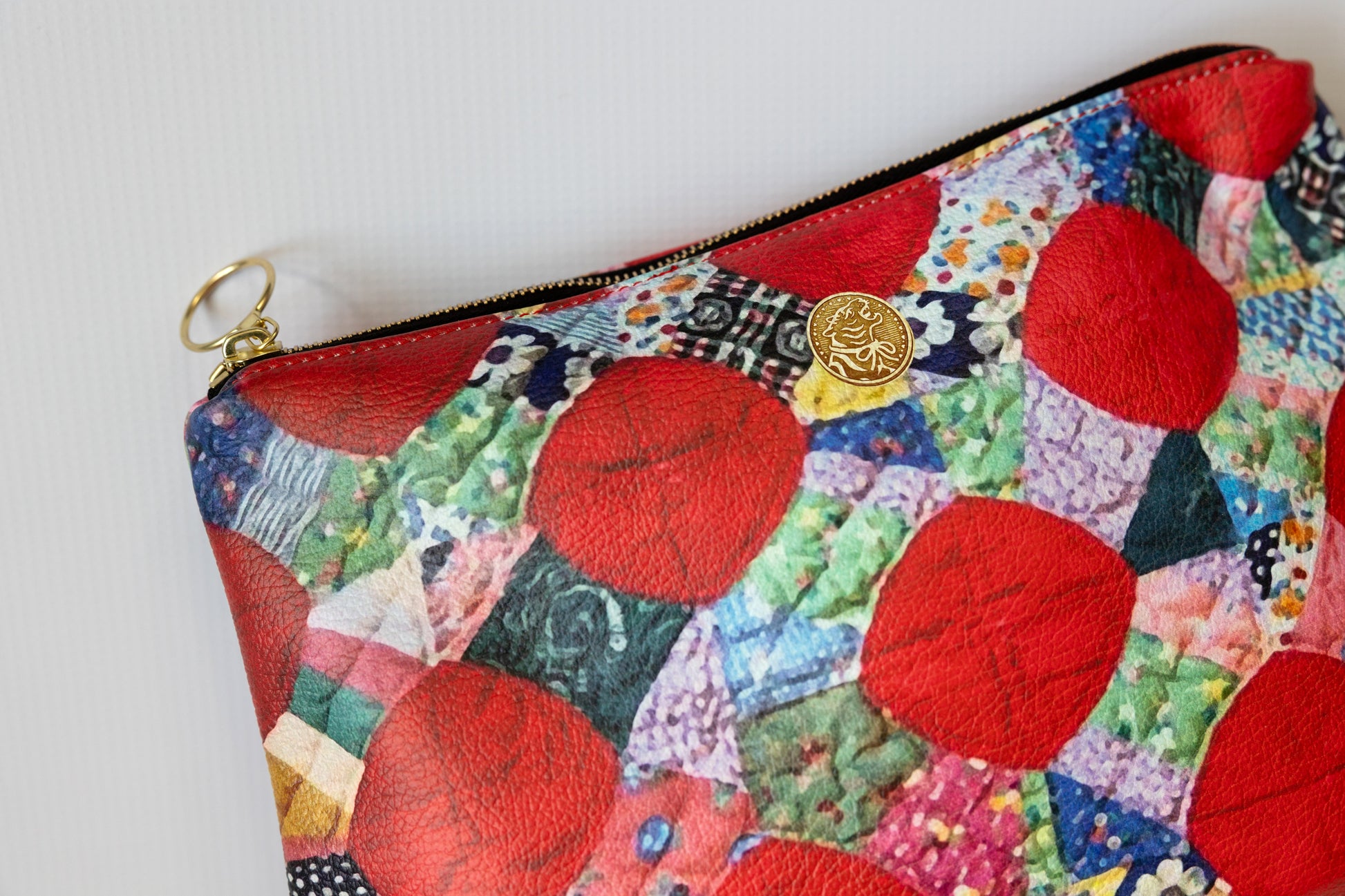 Colorful patchwork pouch with red circular patterns on a white background