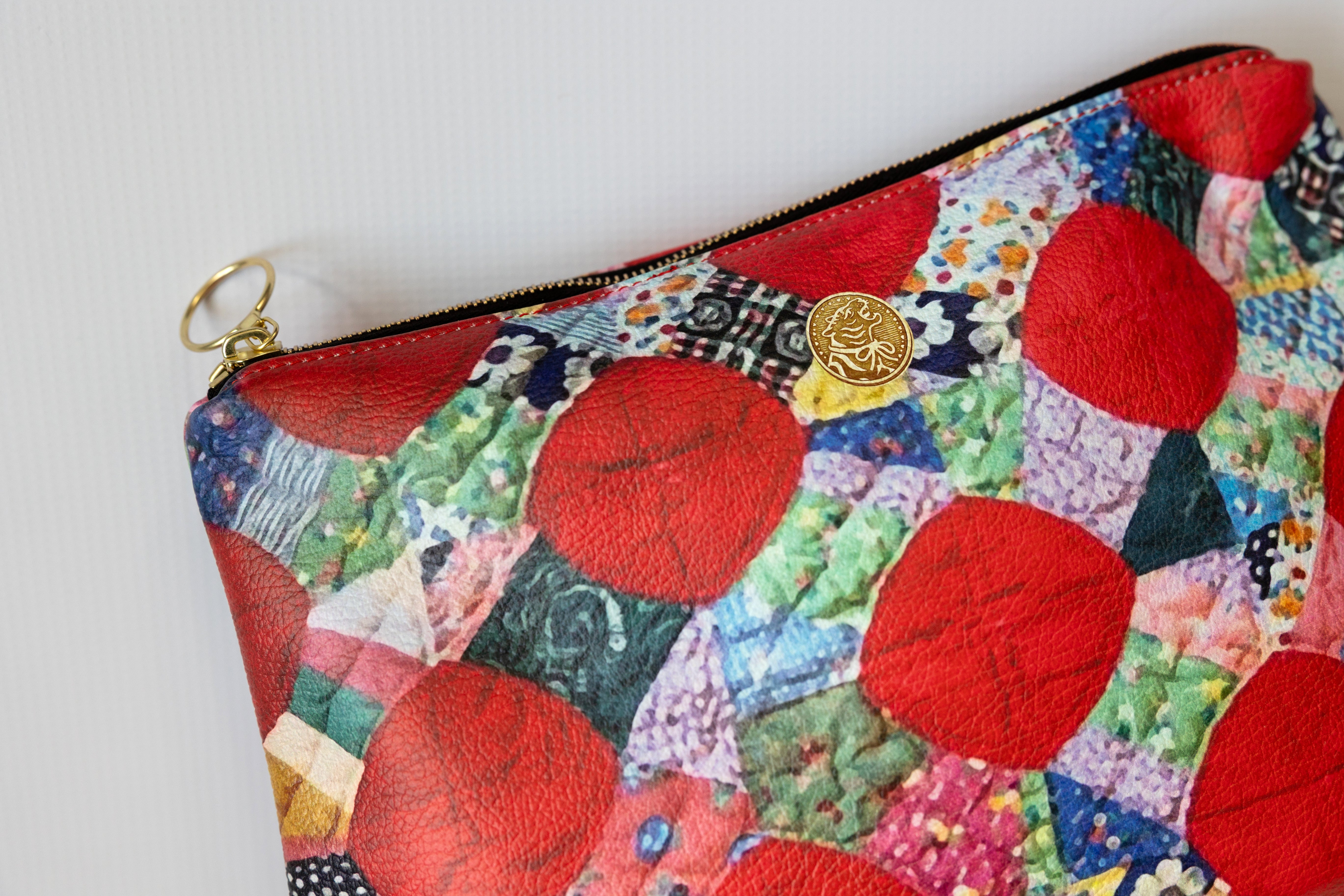 Colorful patchwork pouch with red circular patterns on a white background