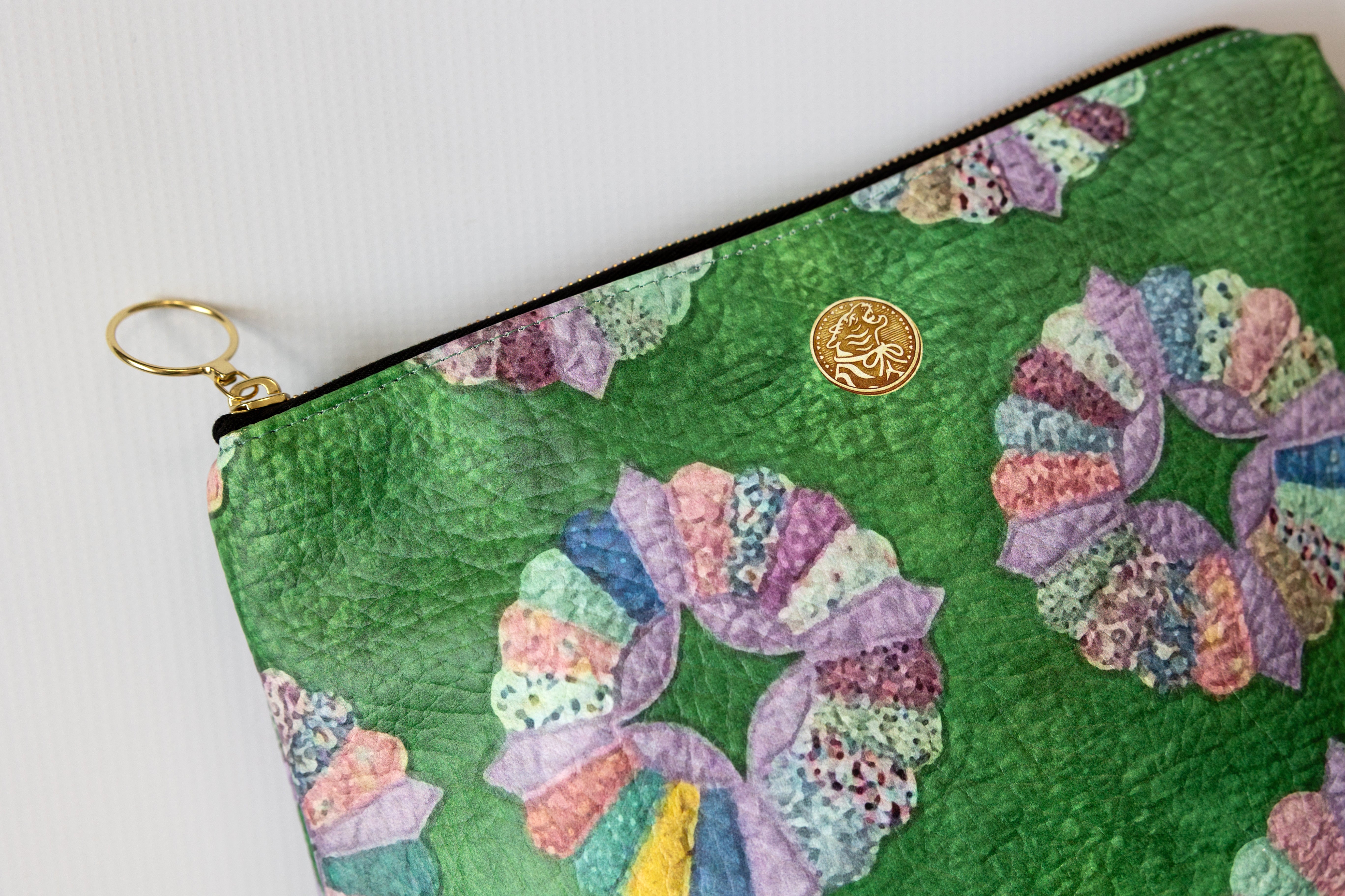 Green pouch with colorful floral patterns and a gold logo on a white background