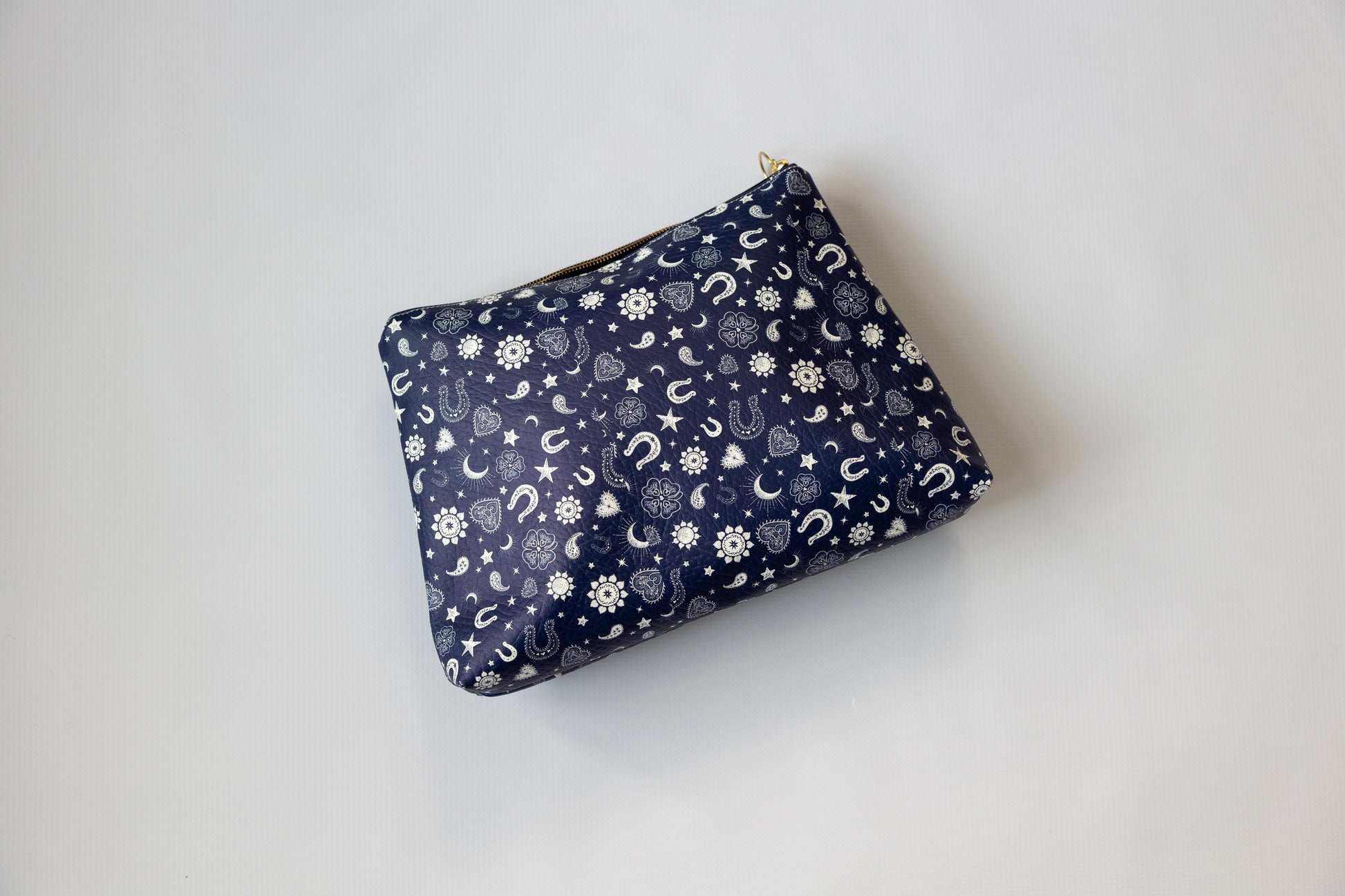 Navy blue pouch with white pattern on a light gray background with stars, sun and horseshoe print