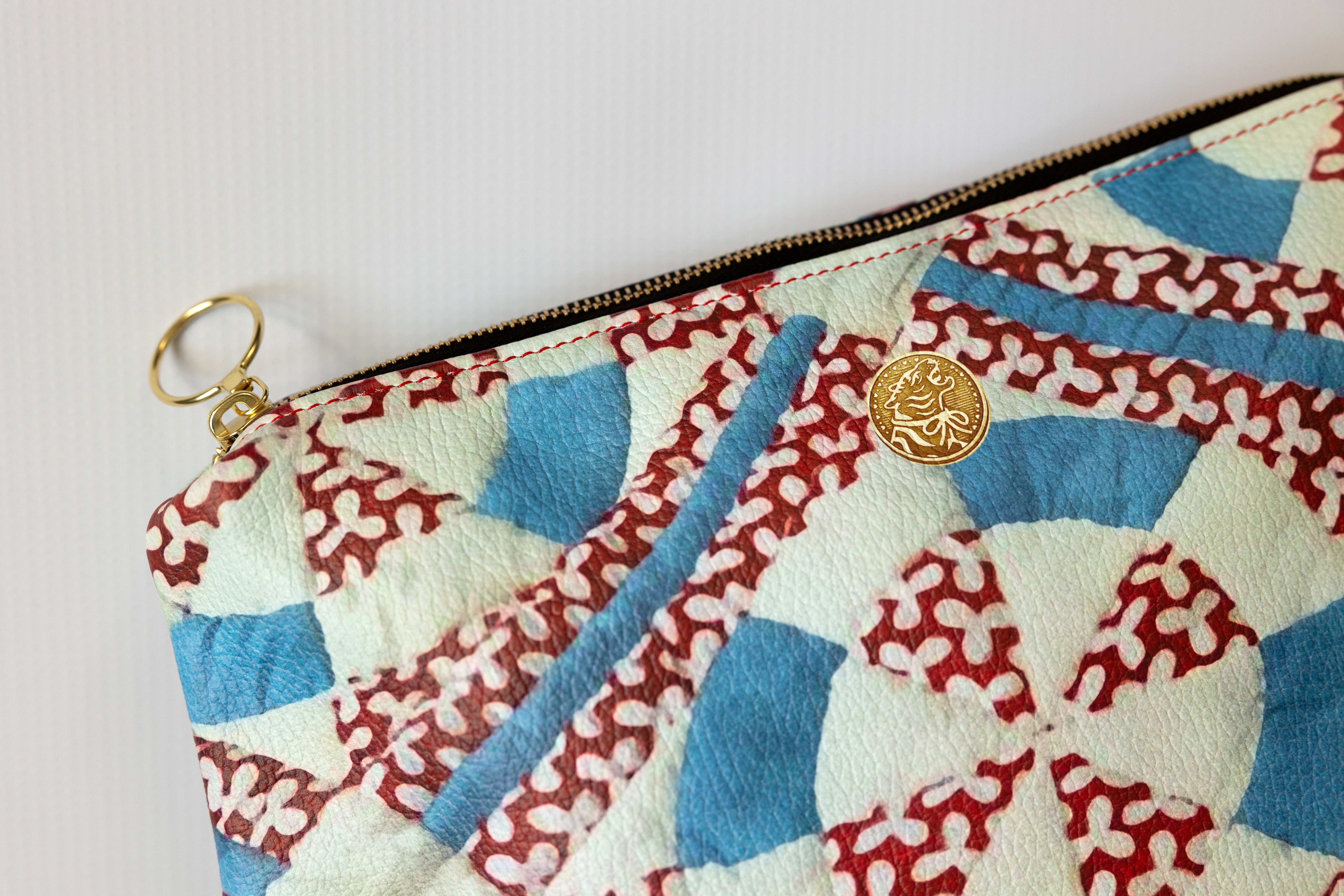 Patterned pouch with zipper and decorative button on a light background