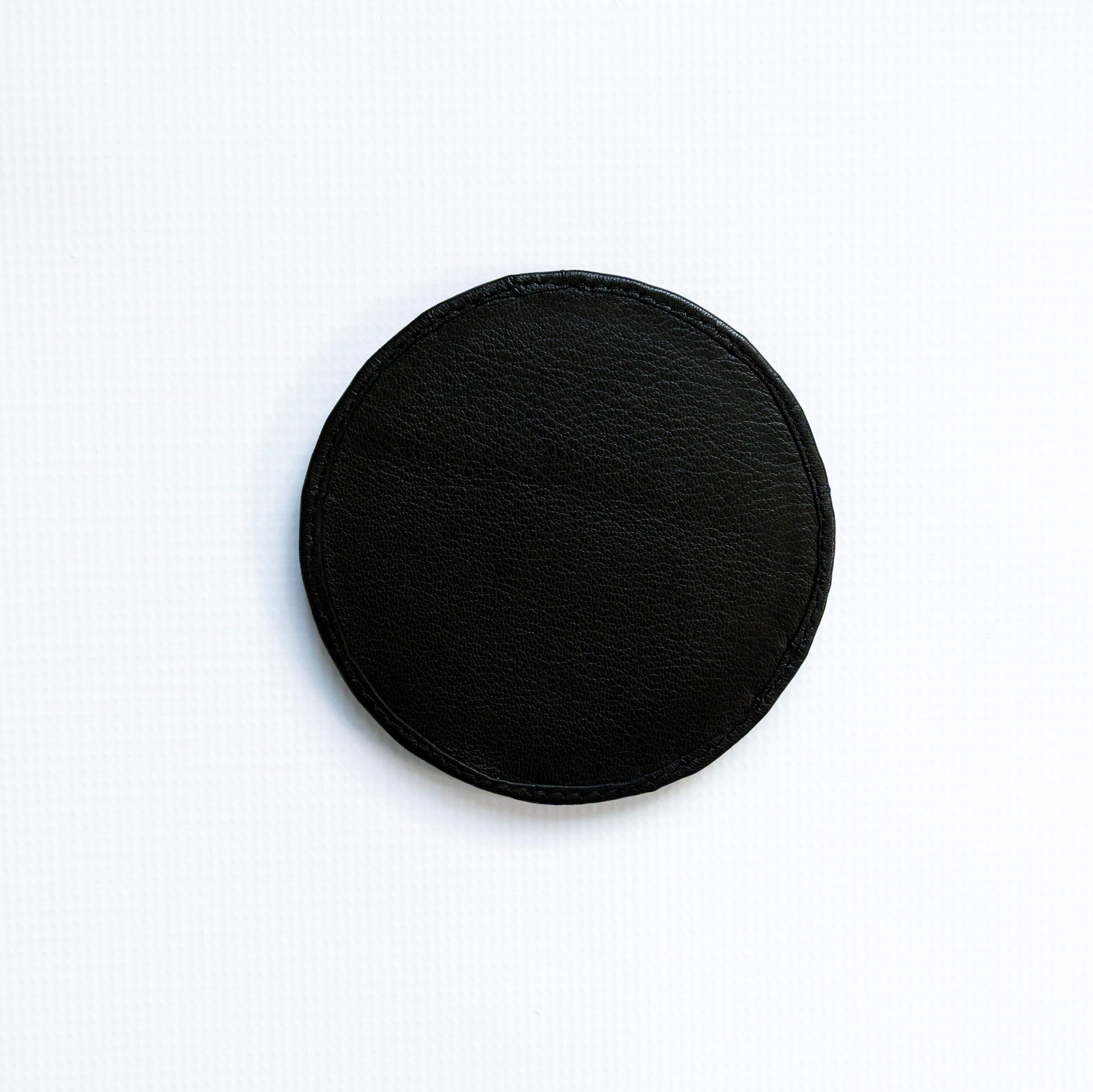 Black circular coaster on a white background