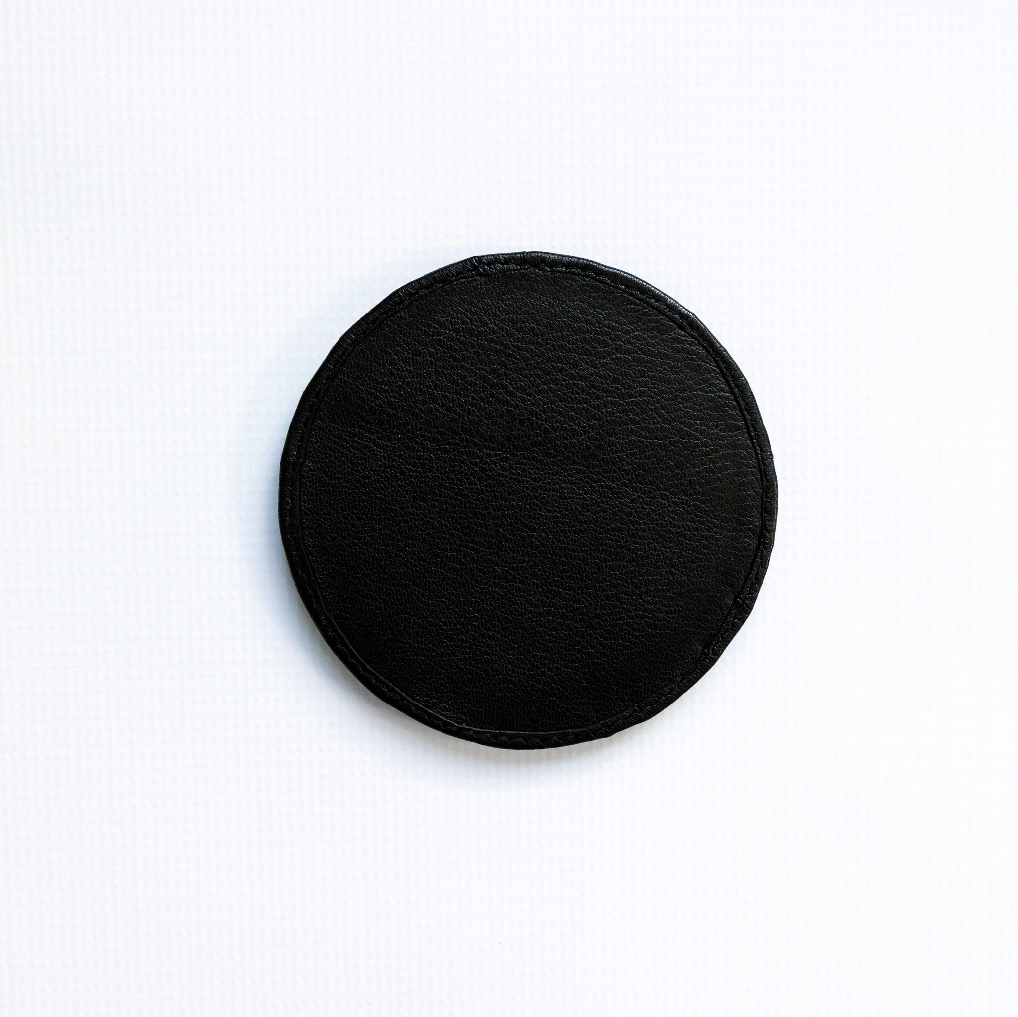 Black circular coaster on a white background