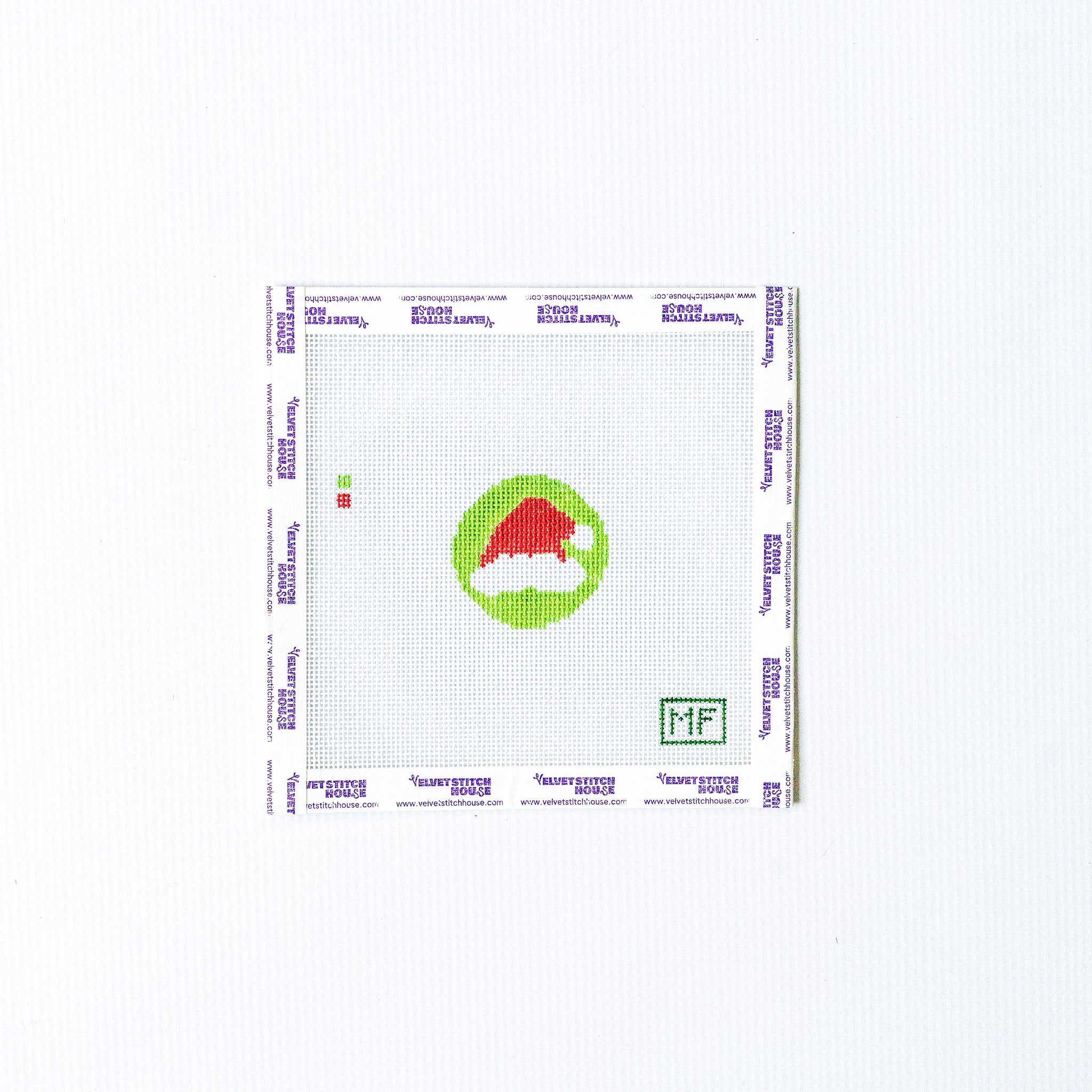 Needlepoint mini pattern with red adn white santa hat on a green background
