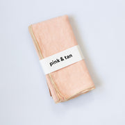 Folded light pink fabric with a 'pink & tan' label
