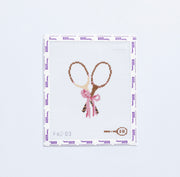 Needlepoint pattern with two vintage tennis rackets tied with a pink bow.