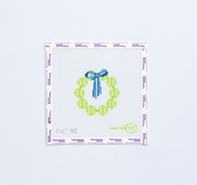 Needlepoint pattern round with yellow tennis balls and blue bow on a white background.